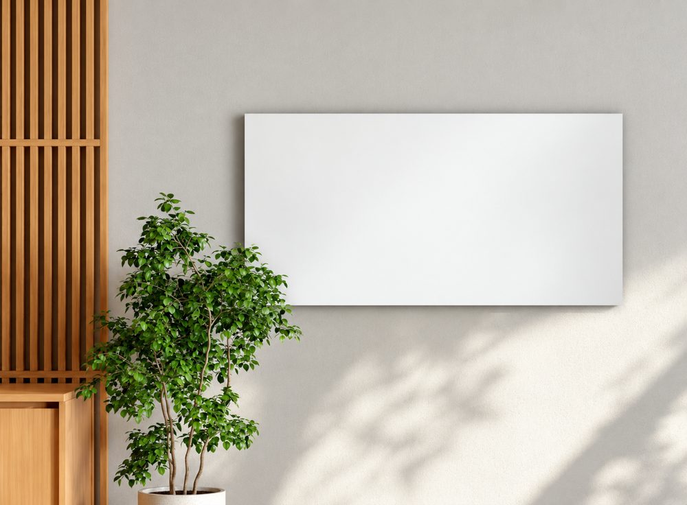 White hybrid infrared heating panel on a wall beside a plant